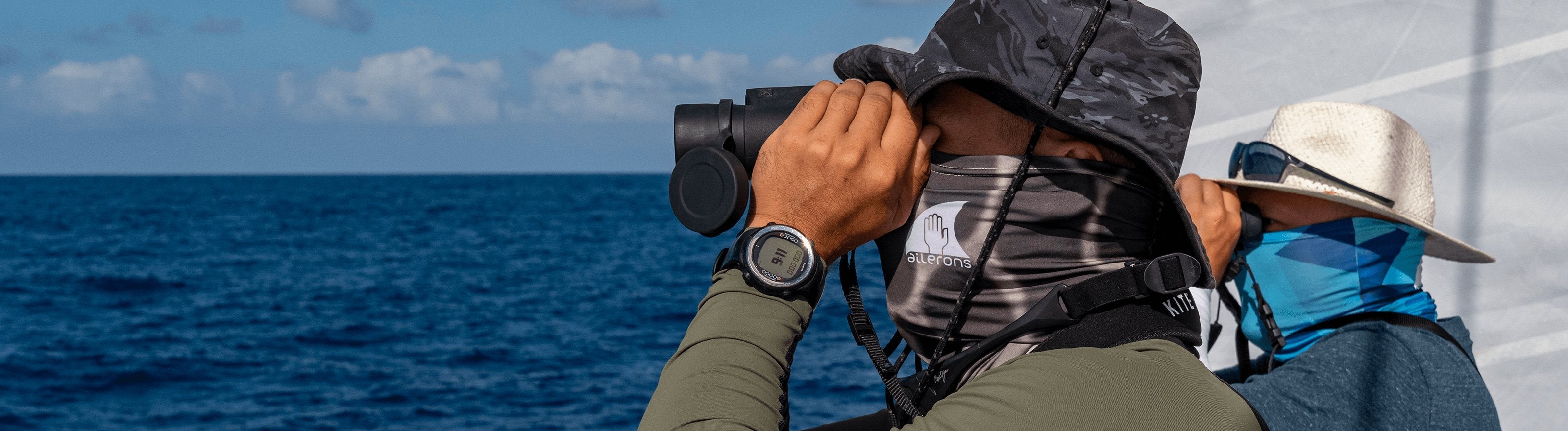 Deux hommes de profil observent la mer aux jumelles depuis un bateau
